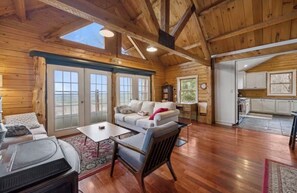 A spacious wooden cabin with a cozy living area featuring a sofa, a coffee table, and a fireplace. - Rustic Mountainside Cabin: “Liberty Lodge” (Liberty)