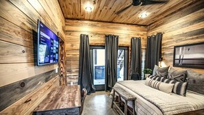 Una camera accogliente con soffitto in legno, un letto con copriletto, una scrivania e una TV a parete.