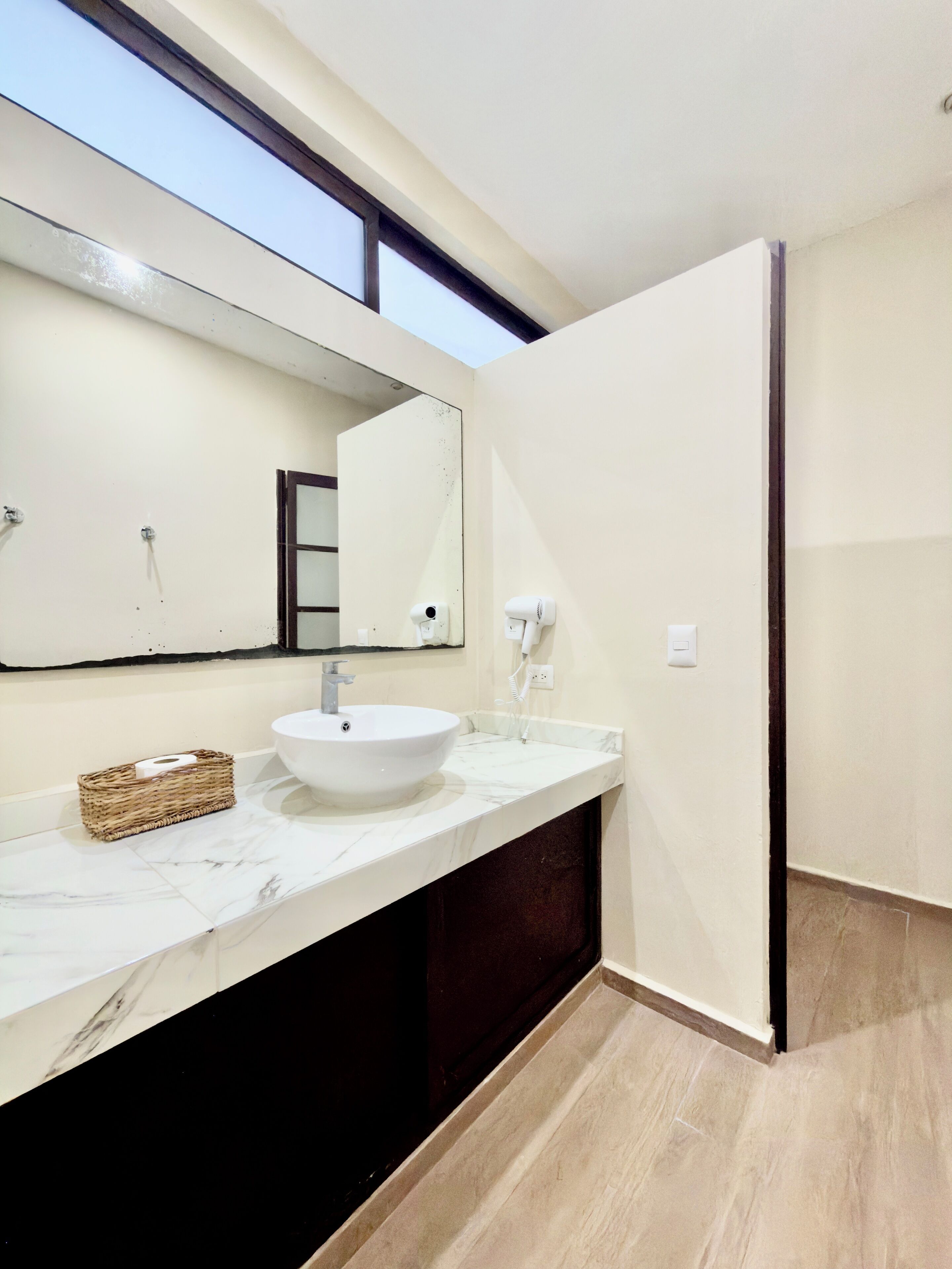 A modern bathroom with a large mirror, a white sink, and a dark cabinet.