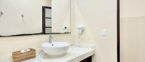 A modern bathroom with a large mirror, a white sink, and a dark cabinet.