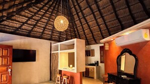Una habitación de hotel con una cama grande, un escritorio, una silla, un espejo y una kitchenette.