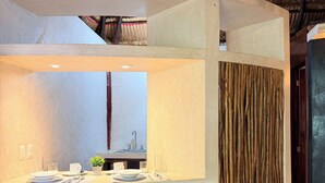 Una cocina moderna con una isla central, dos taburetes de madera y un techo rústico de paja.