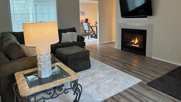 A living room with a fireplace, a television mounted above it, a sofa, a coffee table, and a lamp. - Kozy Keizer Getaway with Fireplace (Keizer)