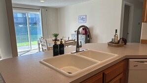 A kitchen with a double sink, wooden cabinets, a coffee bar sign, and a dining area with chairs and a table. - Kozy Keizer Getaway with Fireplace (Keizer)
