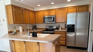 A modern kitchen with wooden cabinets, stainless steel appliances, and a central island. - Kozy Keizer Getaway with Fireplace (Keizer)