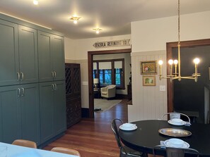 A dining area with a black table, white plates, and a chandelier. There is a cabinet with a glass door and a sign above the door. - Location, Location, Location! Holland Historic District Charmer! (Holland)