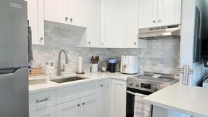 Een moderne keuken met witte kasten, een ingebouwde oven en een koffiezetapparaat.