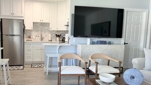 Een moderne keuken met witte kasten, een roestvrijstalen koelkast en een grote flatscreen televisie boven de aanrecht.