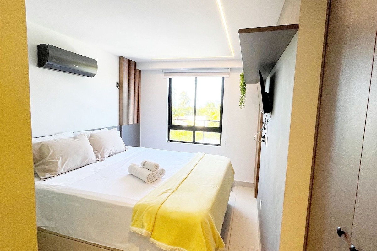 Una habitación de hotel con cama, ventana, aire acondicionado instalado en la pared y puerta.
