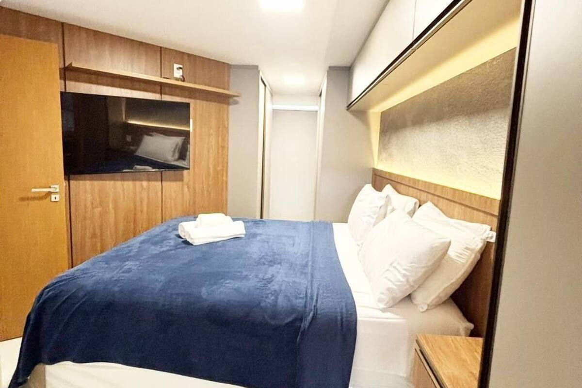 Una habitación de hotel compacta con una cama individual, un armario de madera y una mesita de noche pequeña.