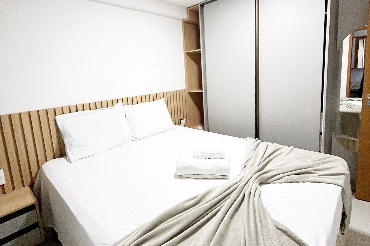 Una habitación de hotel con cama, armario y espejo.