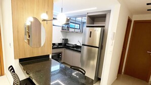 A modern kitchen with a large island, black chairs, and stainless steel appliances. - Dutra Ocean Flat By DayByDay (Joao Pessoa)