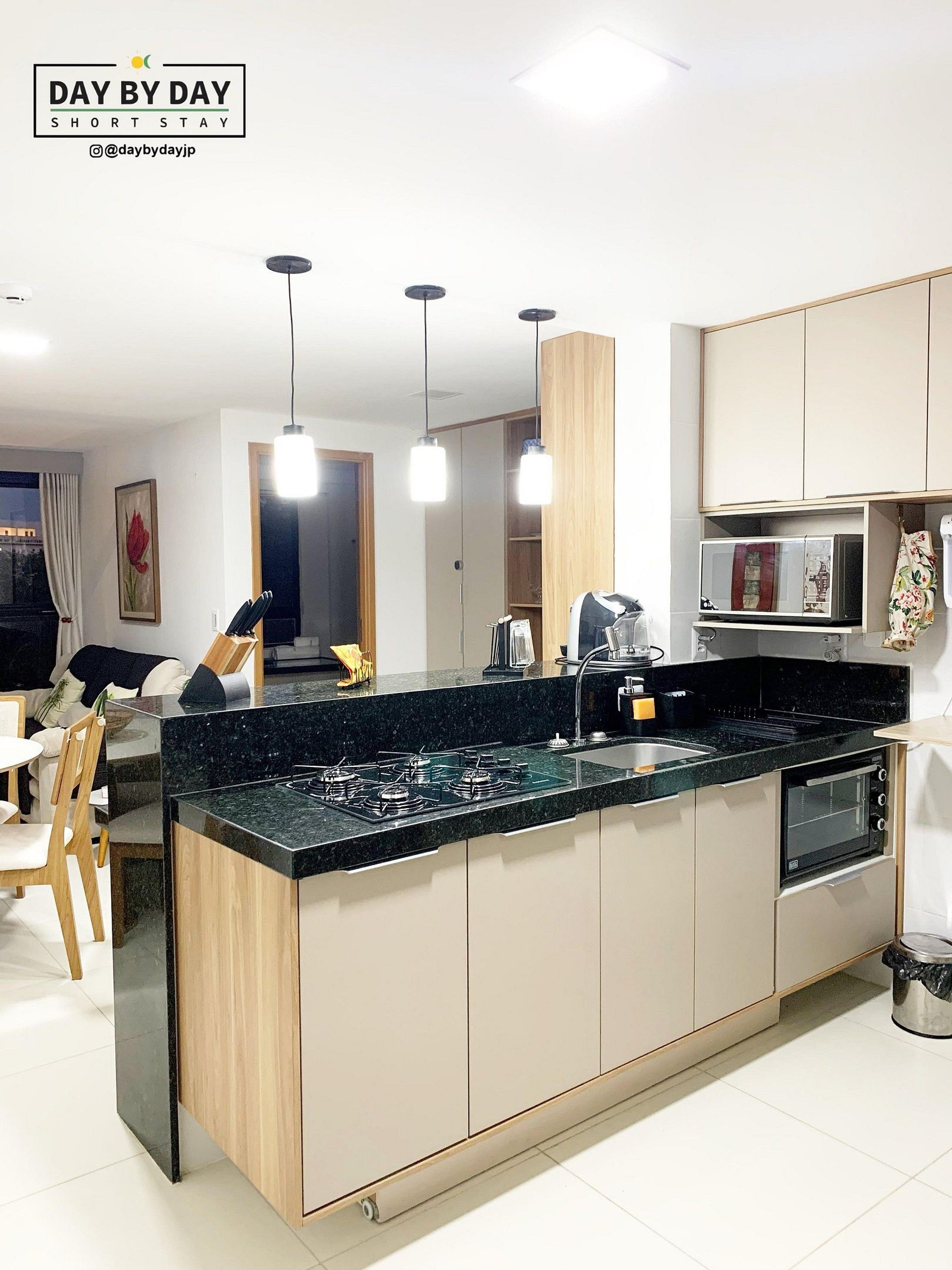 Een moderne keuken met een centraal eiland, inbouwapparatuur, hanglampen en een eethoek met stoelen en een tafel.