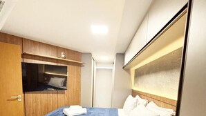 A compact hotel room with a single bed, a wooden wardrobe, and a small bedside table. - Dutra Ocean Flat By DayByDay (Joao Pessoa)