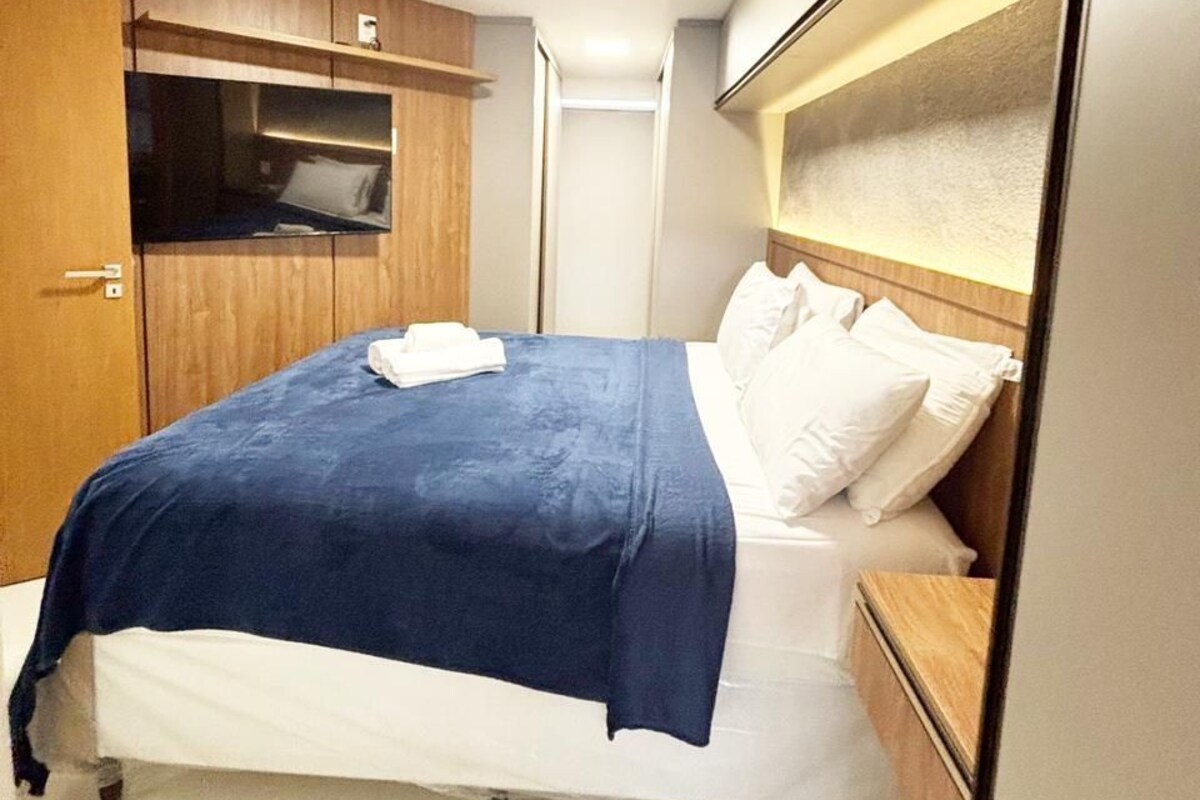 A compact hotel room with a single bed, a wooden wardrobe, and a small bedside table.