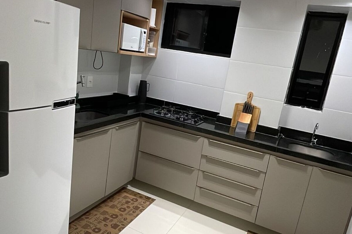 Una cocina moderna con armarios blancos, encimera negra y estufa a gas.