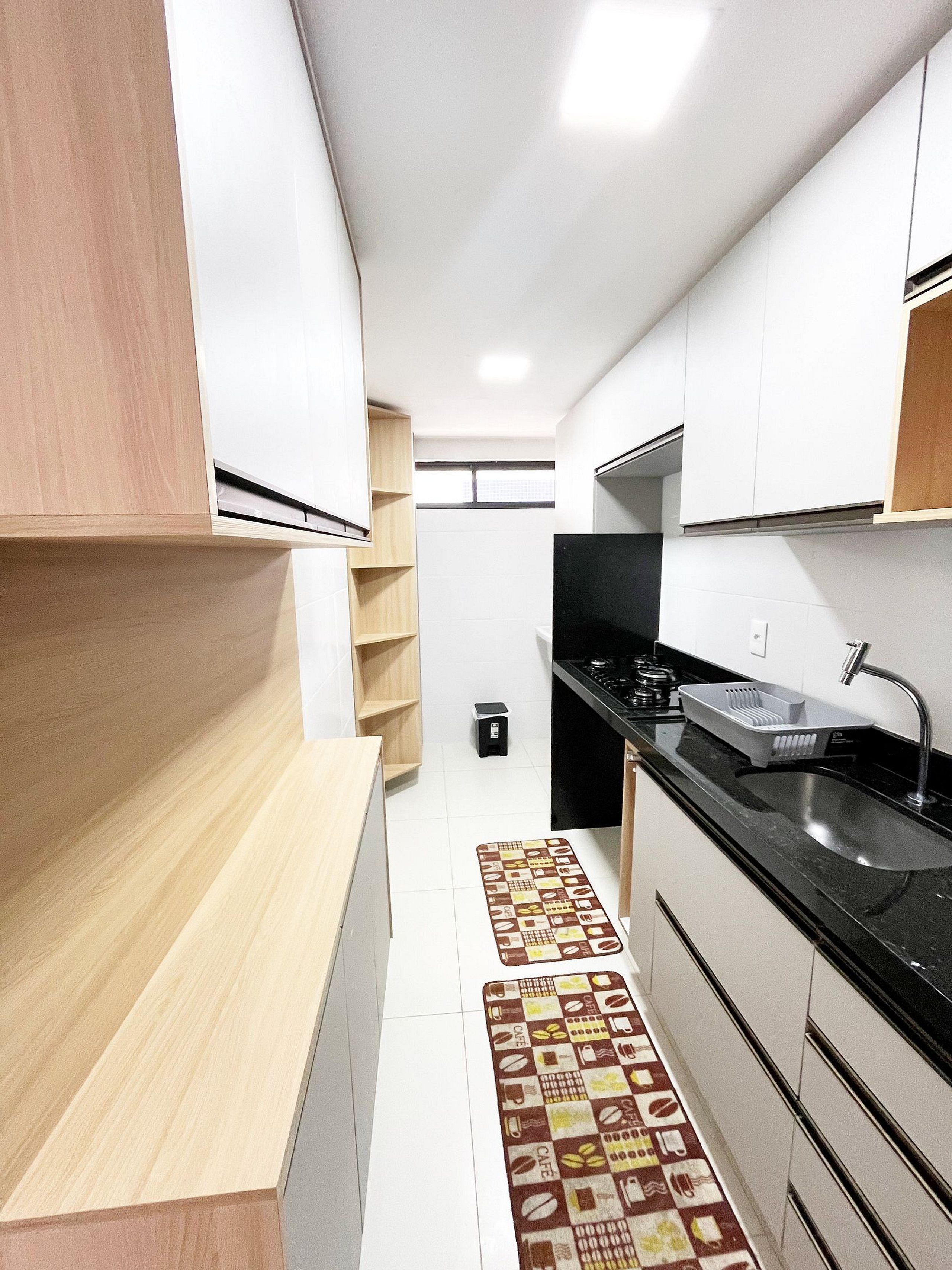 Une cuisine moderne avec des meubles blancs, un plan de travail noir et un tapis à motifs.