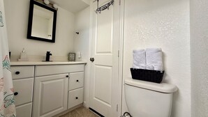 A bathroom with a white toilet, a sink with a mirror above it, and a towel rack with two towels.