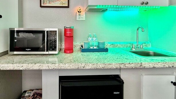 A compact kitchen with a microwave, kettle, and sink.