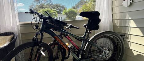 Una bicicleta estacionada en un porche, con vistas a árboles y una casa al fondo.