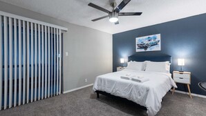 Ein Schlafzimmer mit einem Bett, zwei Nachttischen, einem Deckenventilator und einem Bild an der Wand.