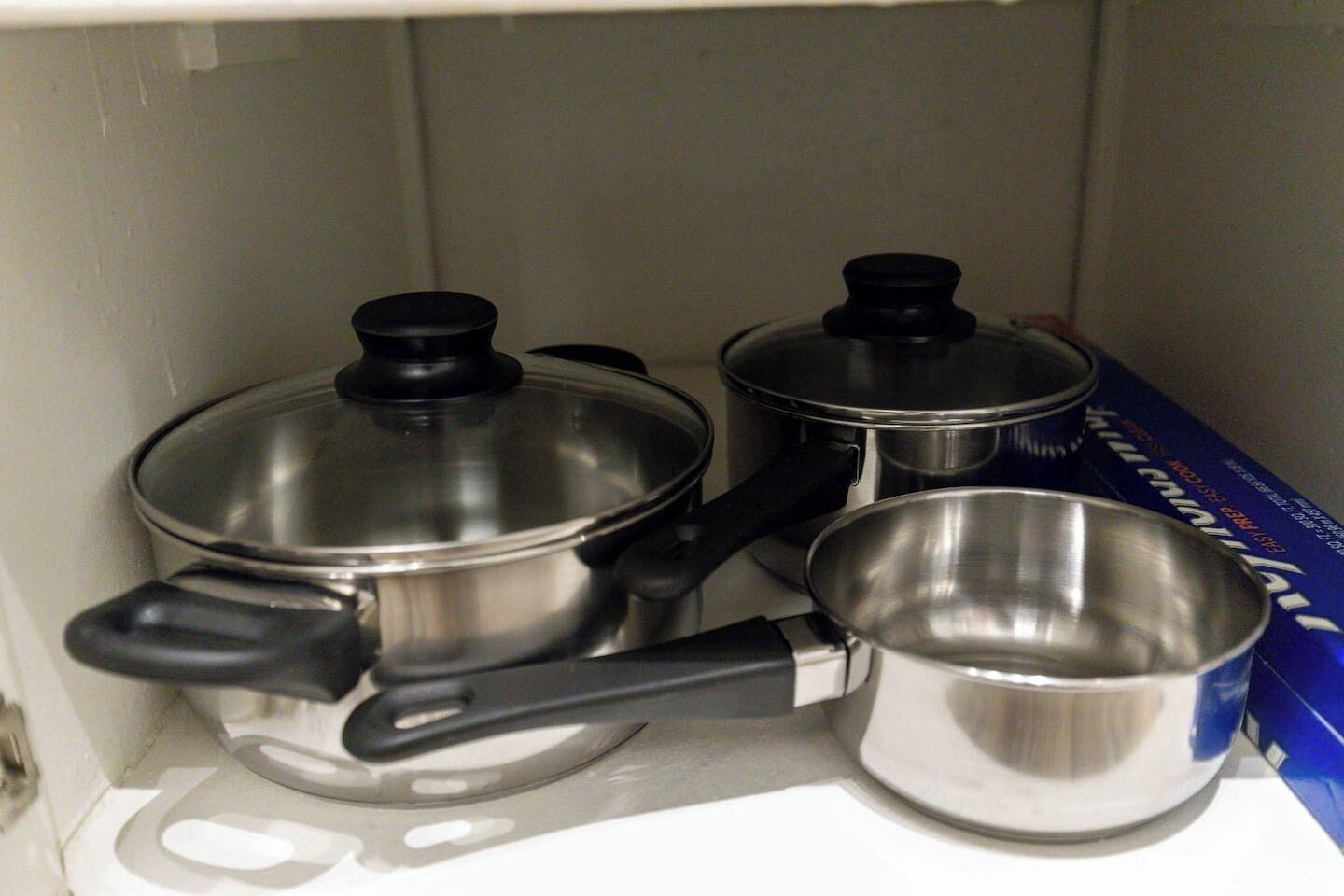 A kitchen with stainless steel cookware, including pots and pans, and a box of paper towels.