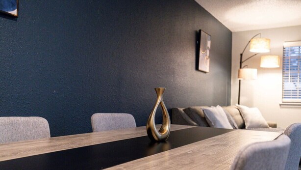 A conference room with a long table, a vase, a sofa, and a lamp. - Arlington 1BR | AT&T, Globe Life, 6 Flags, Parking (Arlington)