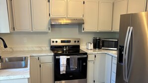 Una cocina moderna con armarios blancos, electrodomésticos de acero inoxidable y suelo de madera.