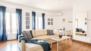 Ein modernes Wohnzimmer mit einem beigefarbenen Sofa, einem Couchtisch und einem Essbereich mit kleinem Tisch und Stühlen.
