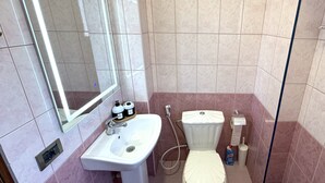 A bathroom with a sink, mirror, toilet, and a trash bin. - Cozy Modern Apartment with Sea View (Sarandë)