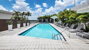 A rectangular swimming pool with a 3 FT depth marker, surrounded by lounge chairs and palm trees, under a clear sky. - Spacious Midtown Miami 2-Bedroom Suite with Bay View (Miami)