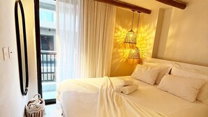 A hotel room with a large bed, a balcony with curtains, and a hanging light fixture. - Csq Jardins By DayByDay (Joao Pessoa)