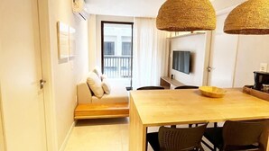 A modern living room with a sofa, a dining table with chairs, and a TV mounted on the wall. - Csq Jardins By DayByDay (Joao Pessoa)