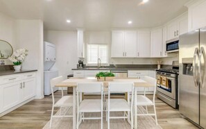 A modern kitchen with white cabinets, a stainless steel refrigerator, and a central island with chairs. - Luxe West LA Designer Condo Near Santa Monica Pier, Beverly Hills & Bel-Air (Los Angeles)