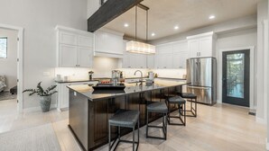 A modern kitchen with a central island, stainless steel appliances, and white cabinetry. - Modern Mountain Getaway Near Park City | Sleeps 15 (Park City)
