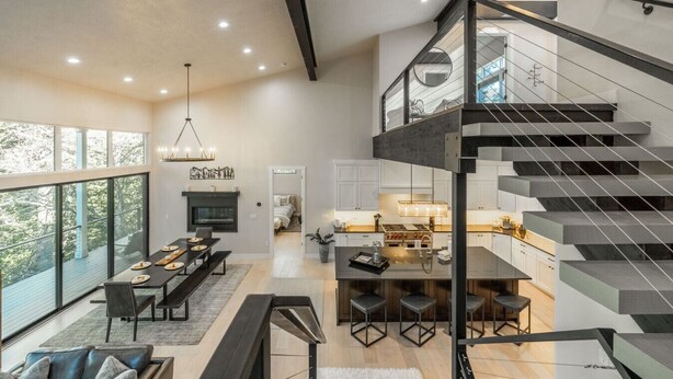 A spacious living area with a dining table, a fireplace, and a modern staircase. - Modern Mountain Getaway Near Park City | Sleeps 15 (Park City)