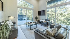 A modern living room with a sofa, coffee table, and a television mounted on the wall. - Modern Mountain Getaway Near Park City | Sleeps 15 (Park City)