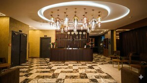 A reception area with a check-in counter, a chandelier, and a check-in desk. - Hôtel St. Eugène (Algiers)