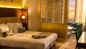 A hotel room with a large bed, a desk, a chair, and a view of the sunset through the window. - Hôtel St. Eugène (Algiers)