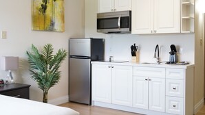 Eine moderne Küche mit weißen Schränken, einem Edelstahlkühlschrank, einer Mikrowelle und einer Kaffeemaschine.