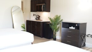 Ein kleines Schlafzimmer mit Bett, einer kleinen Küchenzeile und einem dunklen Kommode.