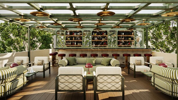 Ein überdachter Außenbereich mit gestreiften Sofas und Tischen, eine Bar mit Regalen voller Flaschen und Blick auf Bäume.