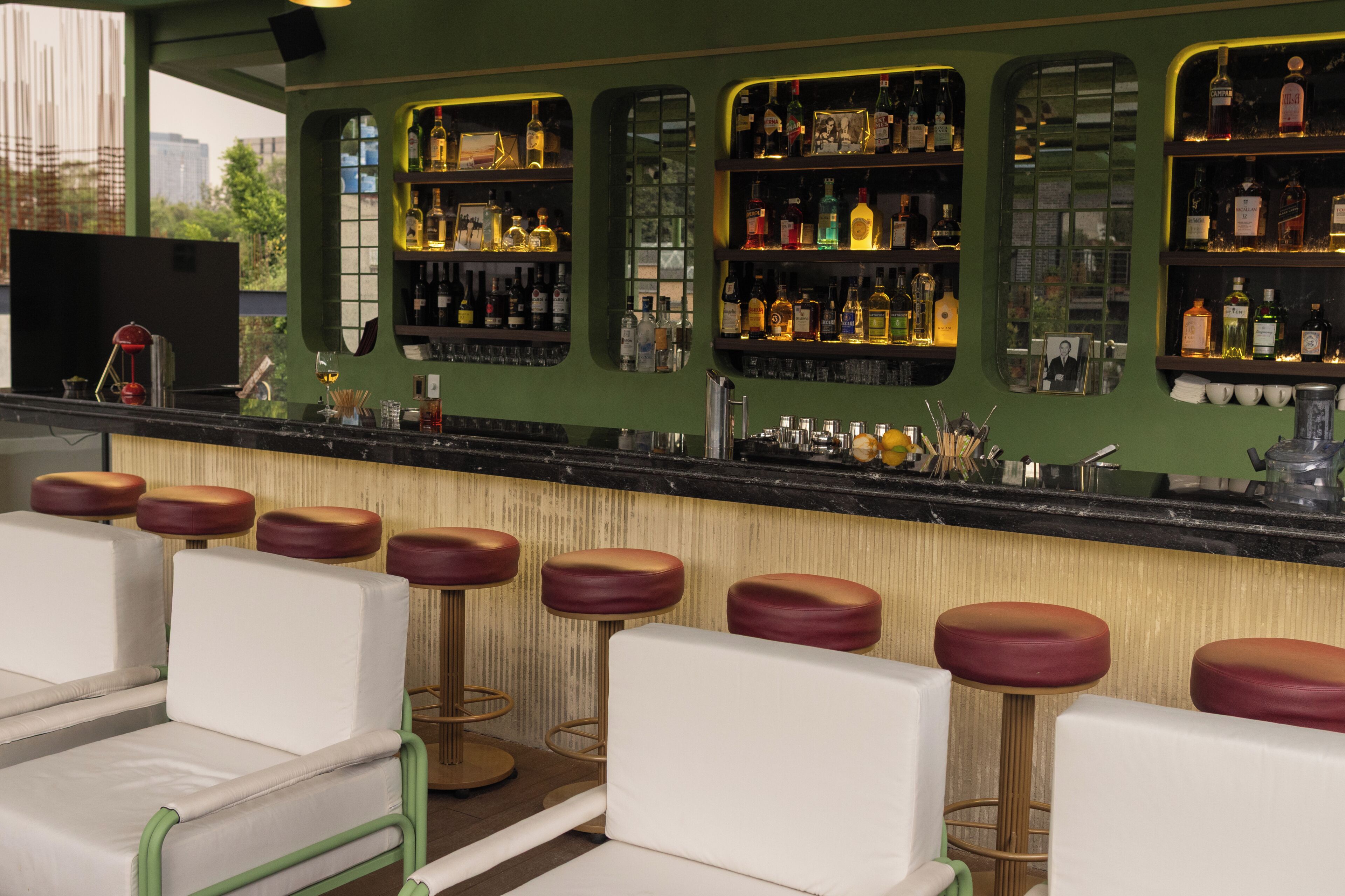 A bar area with multiple stools and a counter displaying various bottles.