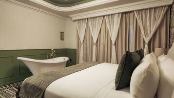 Quarto de hotel com uma cama grande, uma banheira e cortinas.
