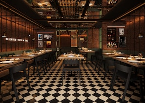 A restaurant with checkered flooring, brick walls, and multiple dining tables set with plates and glasses. - Roma Nueve Dos Hotel Boutique (Mexico City)