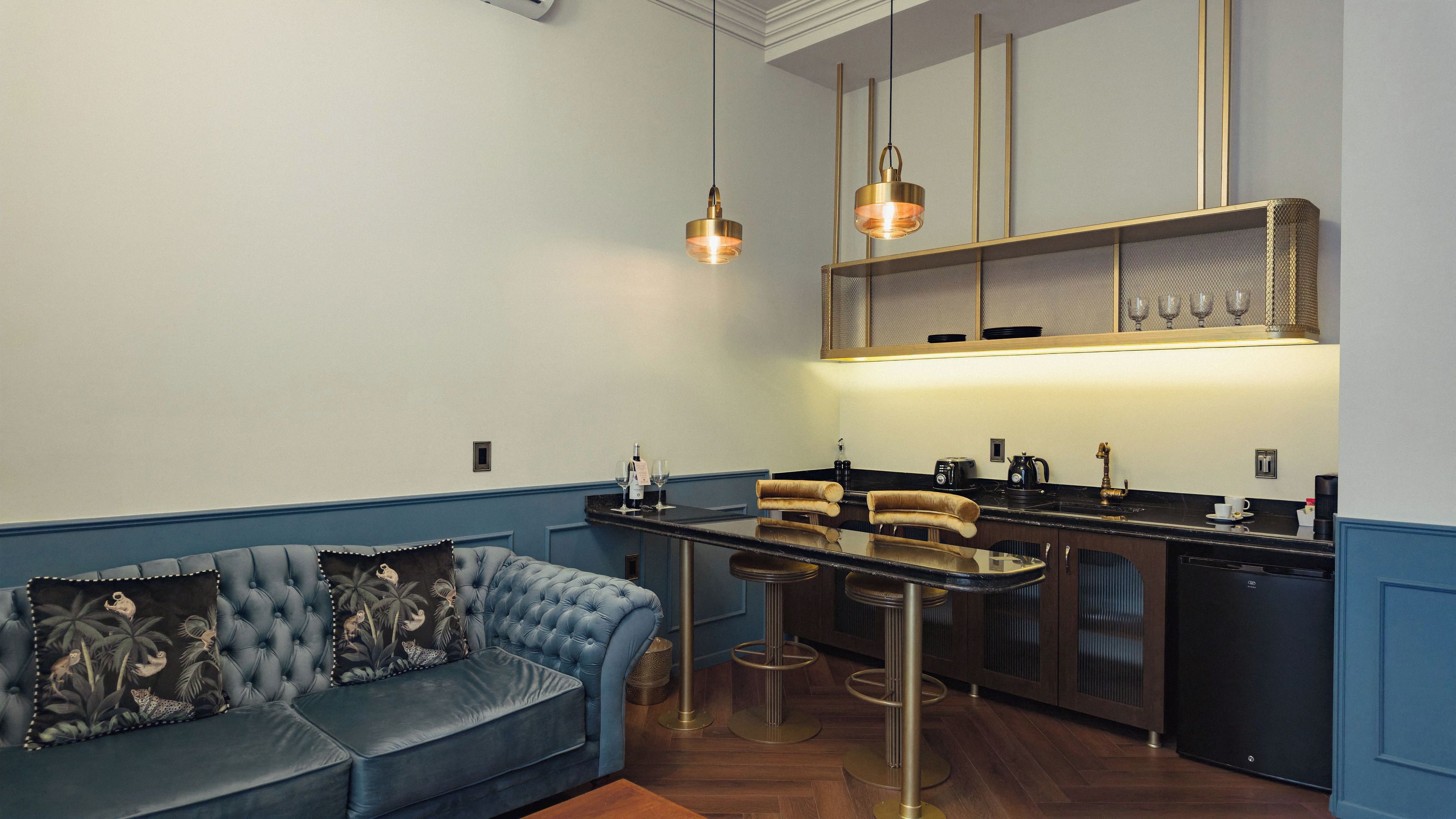Una cocina moderna con barra, un sofá tapizado en azul e iluminación colgante.