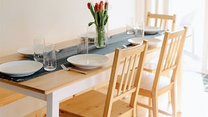 A dining table with chairs, a vase with flowers, and a framed picture on the wall.