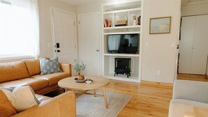 A living room with a sofa, a coffee table, a television, and a fireplace.