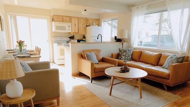 A living room with a sofa, armchair, coffee table, and a dining table with chairs.