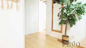 Une pièce avec un plancher en bois, un grand miroir et une plante en pot.